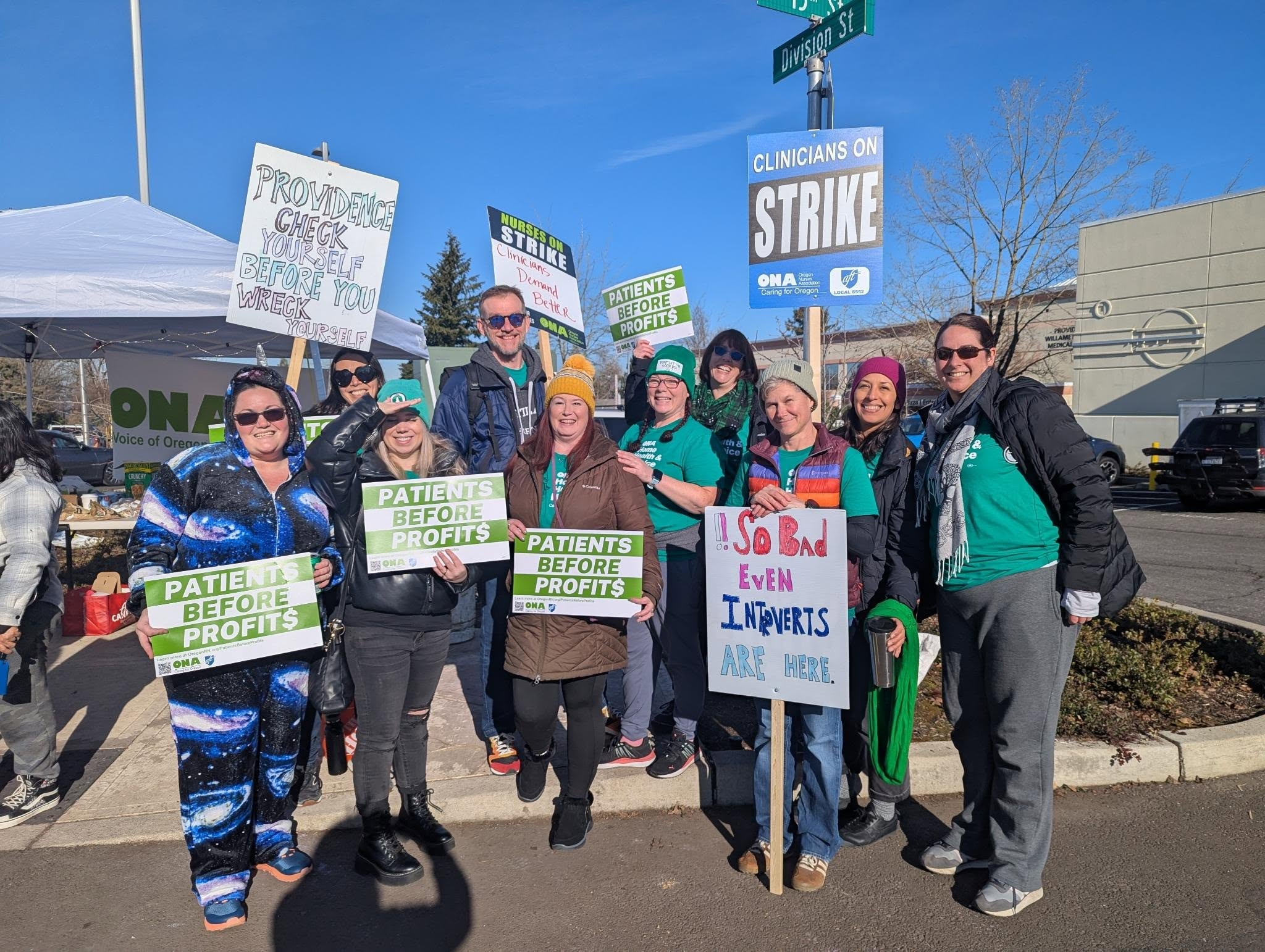 Group of hospitalists holding picket signs with nursing union siblings