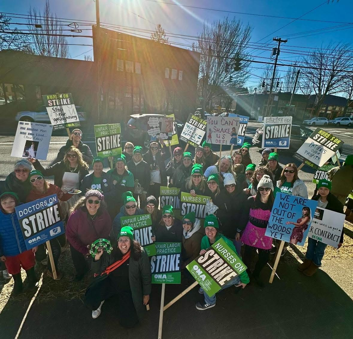 Group of hospitalists holding picket signs with nursing union siblings